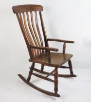 A 19th century elm and beech rocking chair with lathe back, swept arm supports and solid seat on
