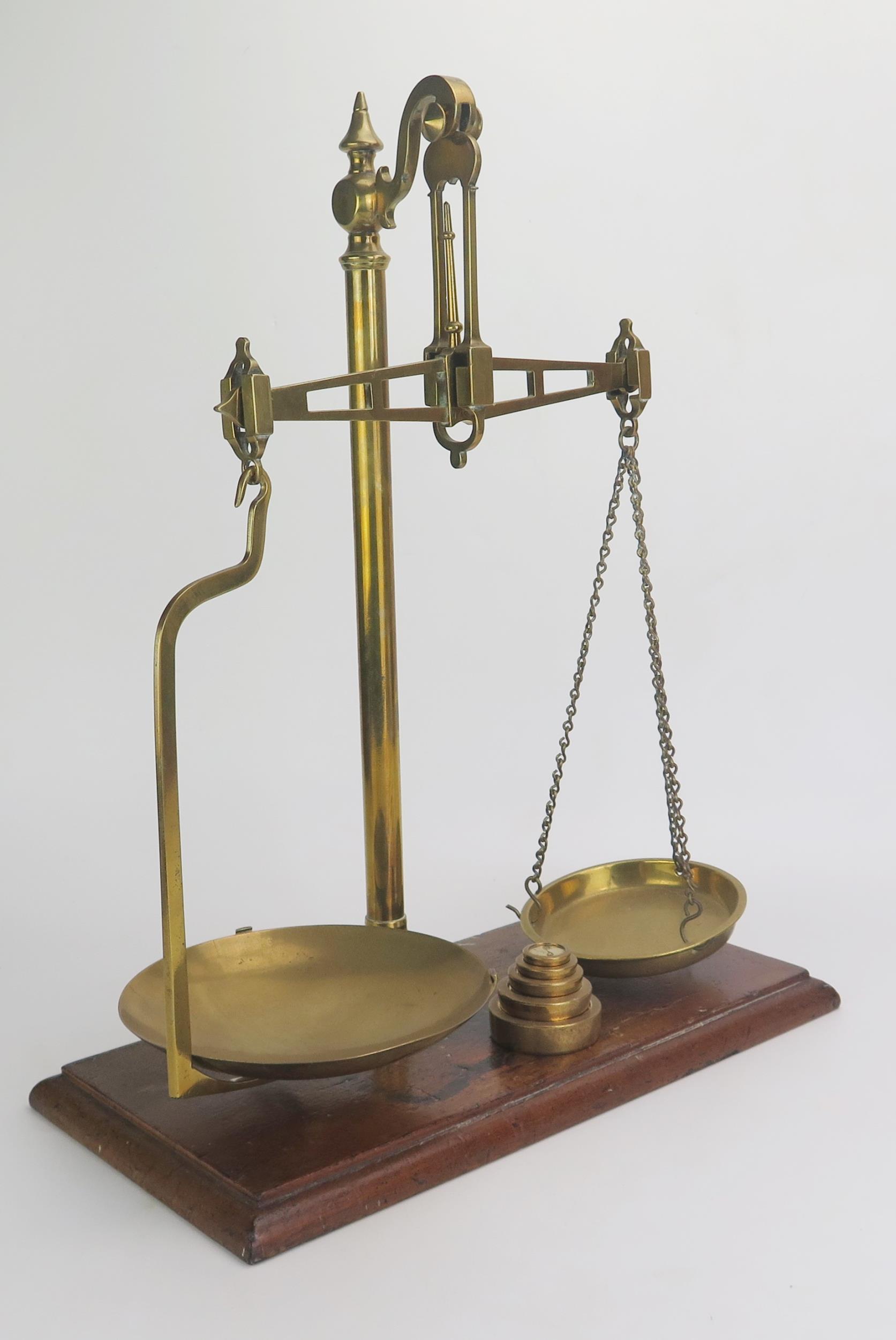 A pair of lacquered brass balance scales, mounted on a rectangular polished wood base, with five - Bild 2 aus 2