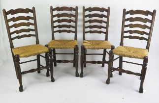A set of four elm ladder back dining chairs, with sisal seats raised on turned legs linked by