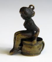 A novelty bronze cigar cutter in the form of a nude lady seated on a chamber pot, 3.5cm high.