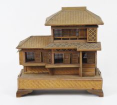 A Japanese wood model of a two storey house, with sliding doors, veranda with woven pitched roofs,