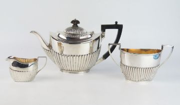 A matched three-piece tea service, various makers and dates, of oval outline with half reeded