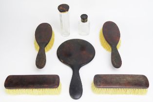 A faux tortoiseshell dressing table set including hand mirror, hair brushes, clothes brushes and