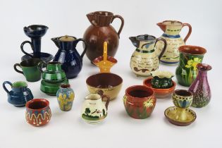 A collection of Watcombe pottery wares includes motto wares, jugs , bowls etc