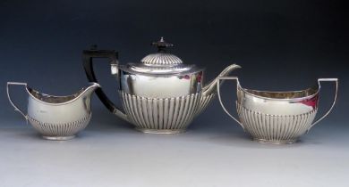 A matched three-piece tea service, various makers and dates, of oval outline with half reeded