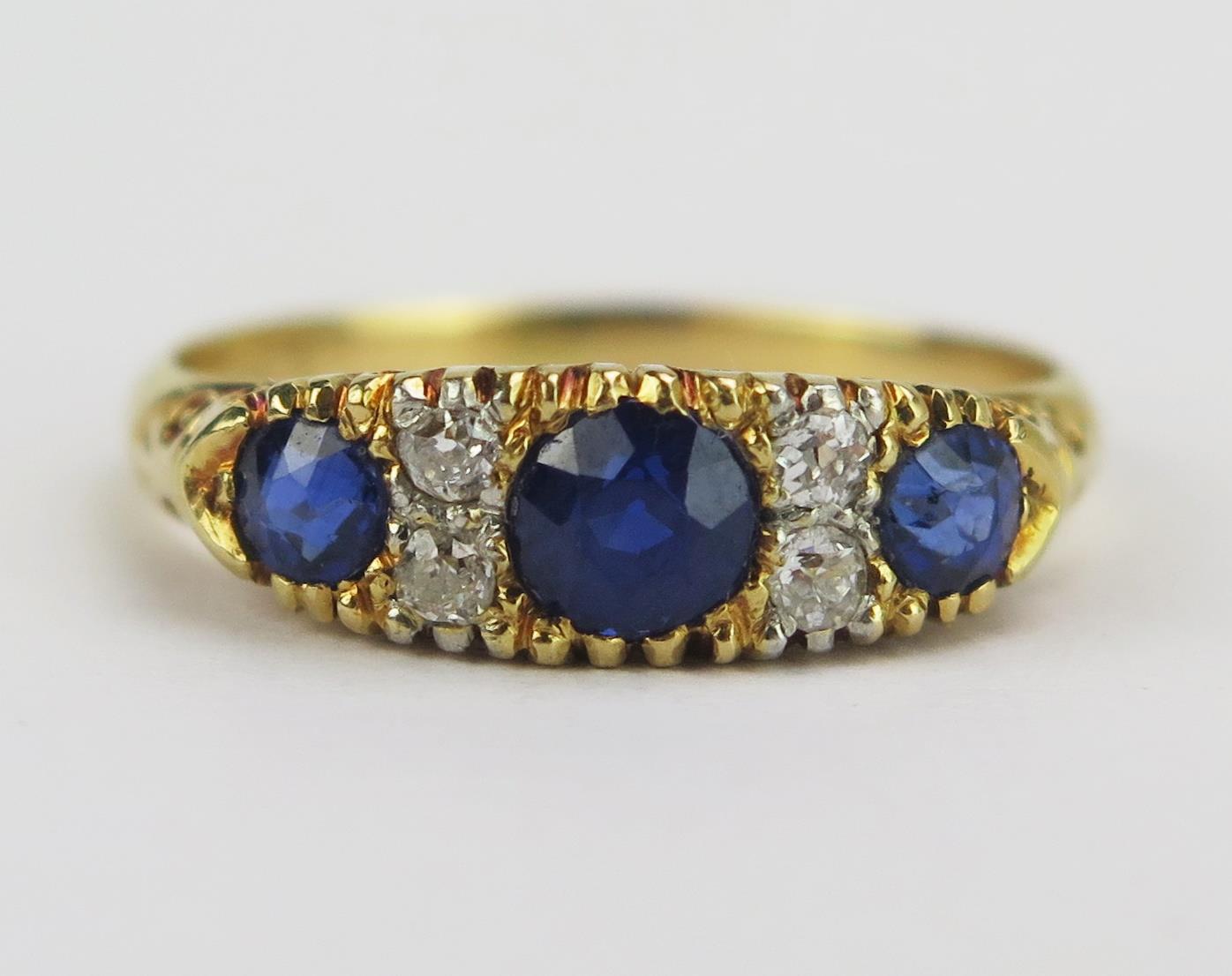 An 18ct Gold, Sapphire and Diamond Ring with scrolling decoration to the shank, 4.2mm principal