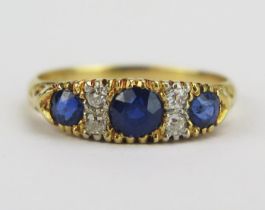 An 18ct Gold, Sapphire and Diamond Ring with scrolling decoration to the shank, 4.2mm principal