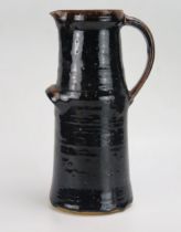 A large pottery jug, possibly by Dora Lunn, of cylindrical outline with tenmoku glaze, 31cm high.