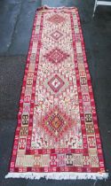 A Kelim flat weave runner, with five hooked lozenge medallions to an ivory ground decorated all over