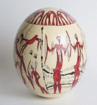 An ostrich egg, decorated with painted tribal warriors and hunting scenes,