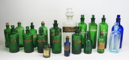 A collection of green, blue and clear glass pharmaceutical bottles, various sizes.