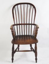 A 19th century elm Windsor style elbow chair with arched stick back, solid seat on turned under