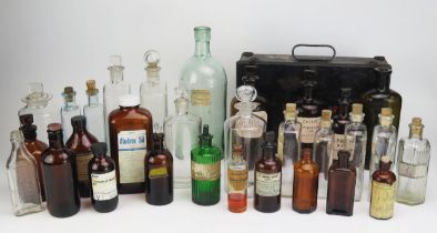 A collection of clear and brown glass pharmaceutical bottles, medicine bottles, metal first aid