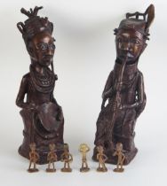 A pair of Benin bronze figures of a seated man with pipe and woman with fan, 31cm high, together