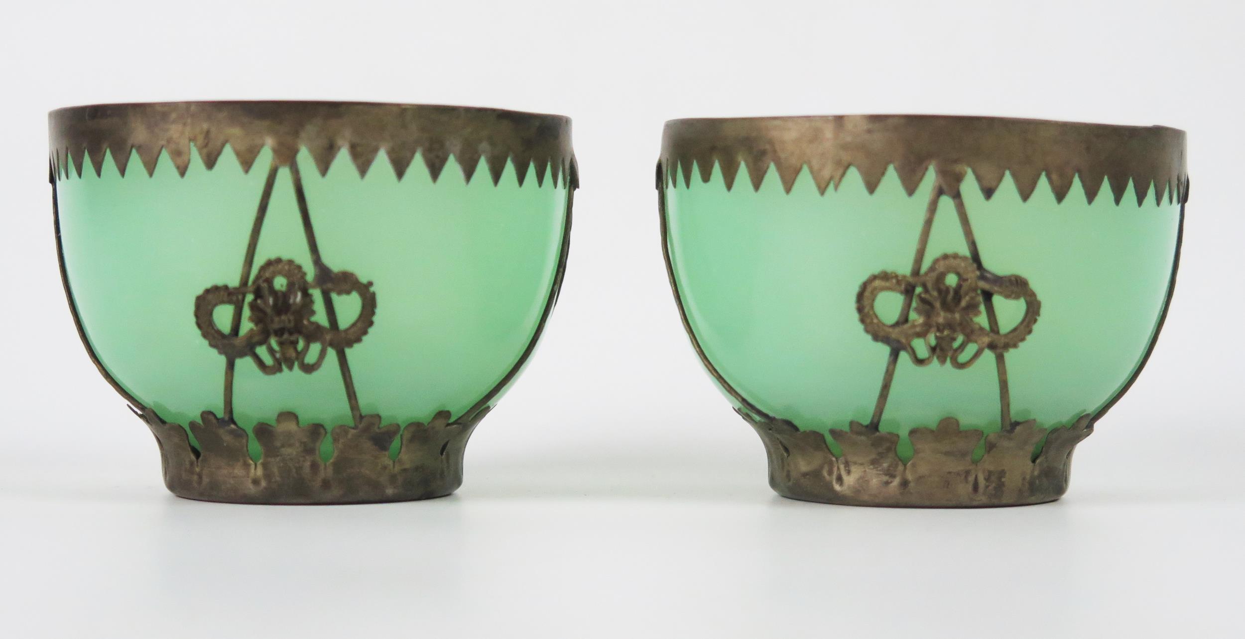 A pair of green glass bowls with white metal mounts, 7cm diameter.