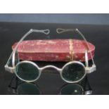 A pair of silver framed sun glasses with double hinged green glass lenses, contained in a Morocco