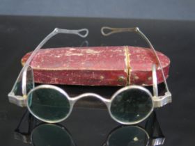 A pair of silver framed sun glasses with double hinged green glass lenses, contained in a Morocco