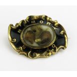 A Victorian Yellow Metal and Enamel Memorial Brooch with a central glazed panel containing a lock of