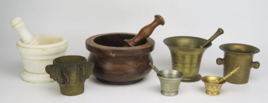 A turned wood pestle and mortar, three small brass mortars and an alabaster pestle and mortar.