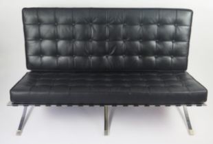 A black Barcelona style sofa, with button down loose cushions, on a chrome X-frame with swept