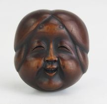 A Japanese carved boxwood netsuke of a female noh theatre mask, signed possibly Gyokushu, to the
