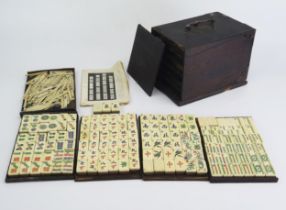 An early 20th century Mah Jong set with bone and bamboo backed tiles, gaming counters, instructions,