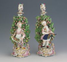 A pair of late 19th century porcelain candleholders in the Chelsea style, decorated with a boy and