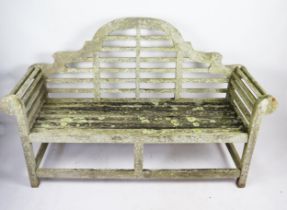 A Lutyens style teak garden seat, with arched rail back, scroll ends, and railed seat, 165cm wide,