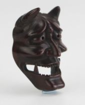 A Japanese carved boxwood netsuke of a noh theatre Hannya mask, signed Doraku, 4.5cm high. Meiji