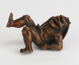 A Japanese carved boxwood netsuke in the form of an oni carrying a shield on his back, signed, 5.