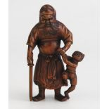 A Japanese carved okimono of Shoki the demon queller, the standing figure with oni in one hand and a