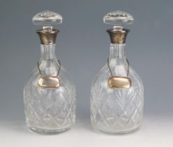 A pair of clear glass and silver mounted decanters of mallet form, with silver collars and