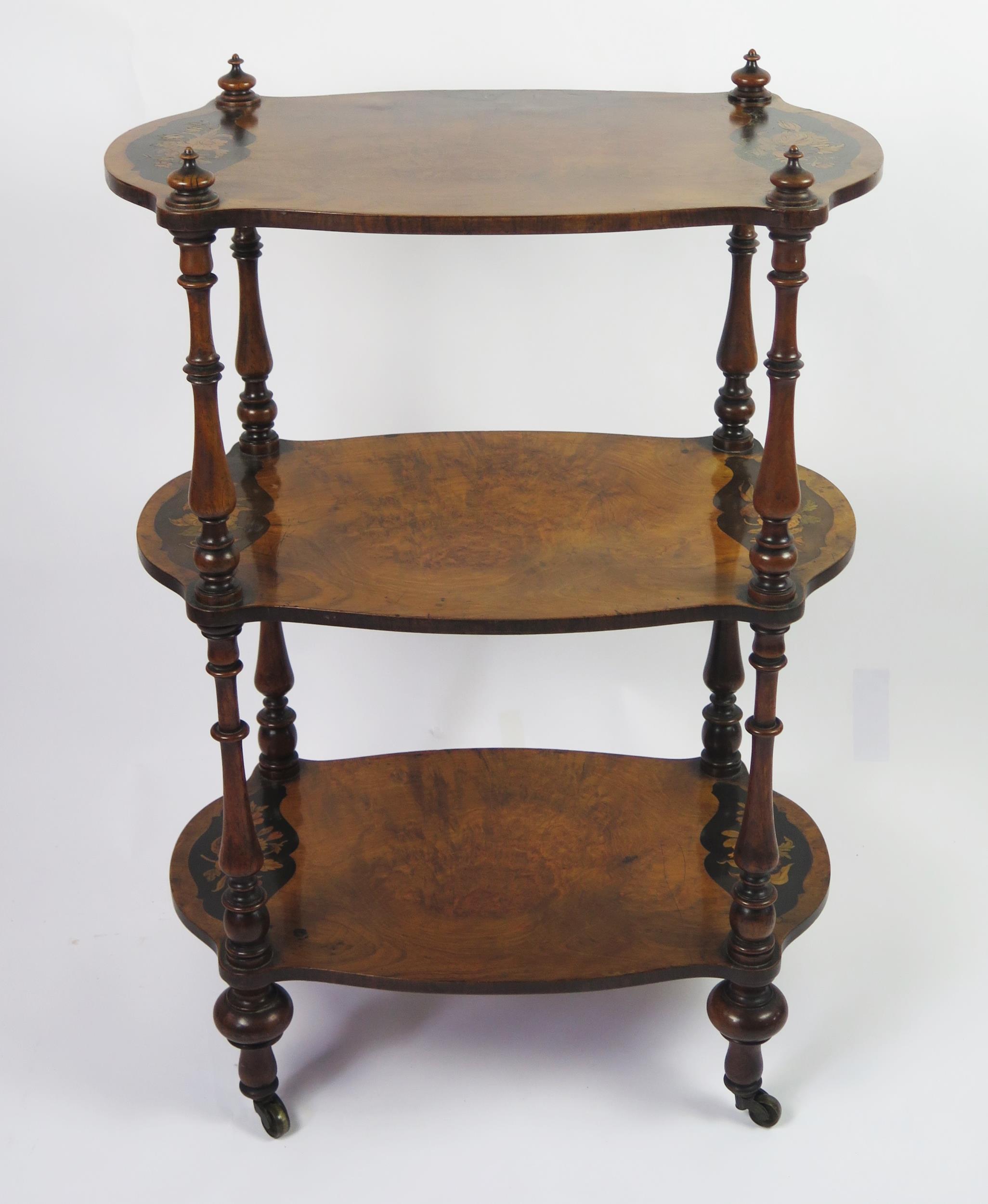 A Victorian walnut and floral inlaid three-tier what not, of cartouche-shaped outline, on ring