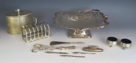 A silver handled shoe horn, plated tea caddy, plated grape shears, toast rack, plated swing