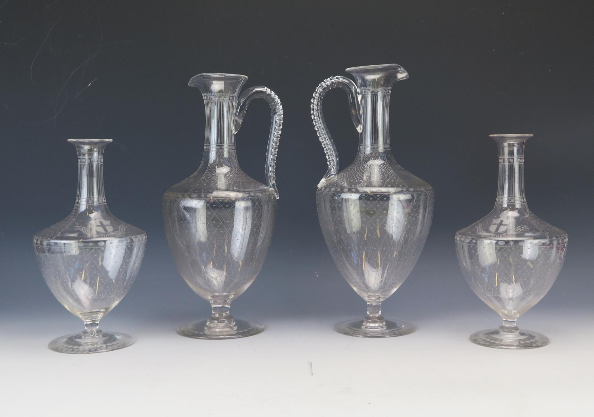 Two Edwardian etched glass wine ewers, of ovoid form with slender neck and scroll handle raised on a