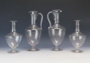 Two Edwardian etched glass wine ewers, of ovoid form with slender neck and scroll handle raised on a