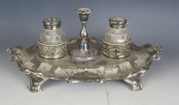 A Victorian plated ink stand, of cartouche-shaped outline, with central taper stick, flanked by