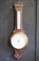 An Edwardian oak cased wheel barometer, or arched outline, with mercurial thermometer, and aneroid