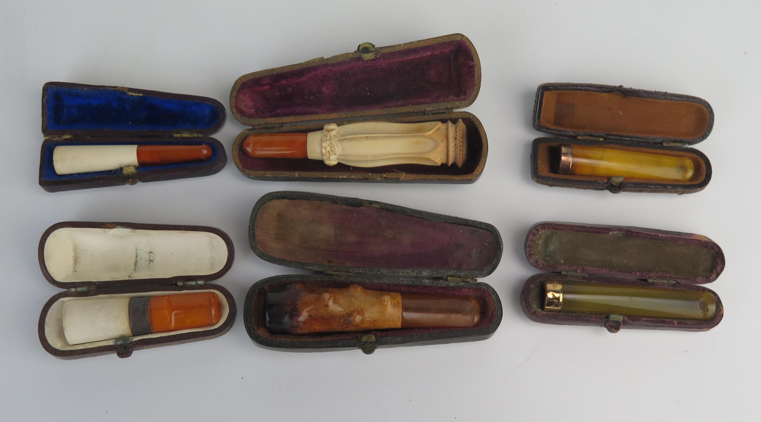 A collection of six assorted amber and other cheroot holders, all cased.