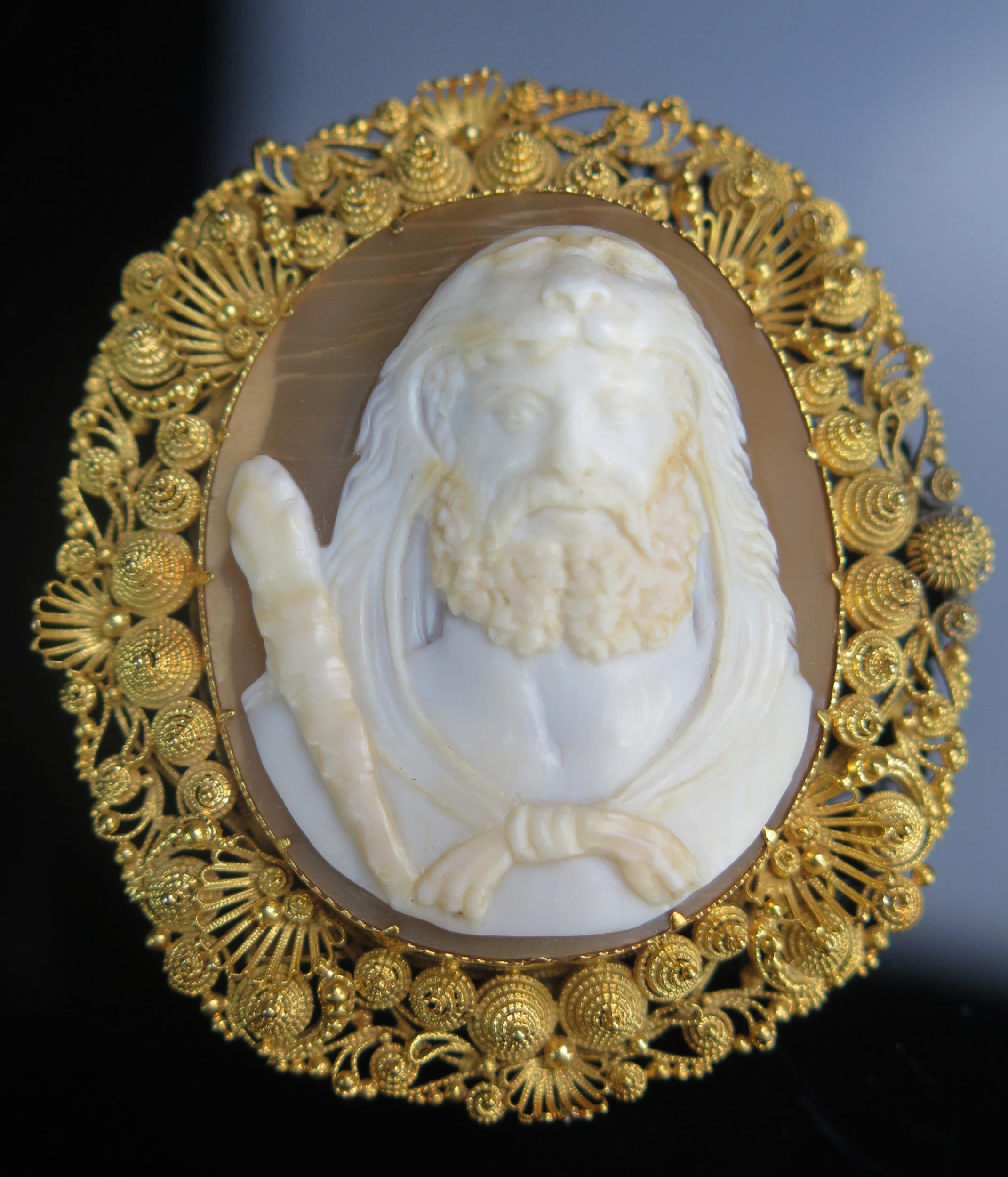 A Shell Cameo Brooch in a precious yellow metal filigree setting, decorated with the bust of