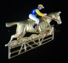 An 18ct Gold and Enamel Horse and Jockey Brooch shown jumping a fence, 32.9mm long, London 1952,