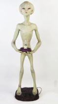 Life Size Alien Resin Figure holding a lamp (wired and working) standing on a purple rock base, 49.