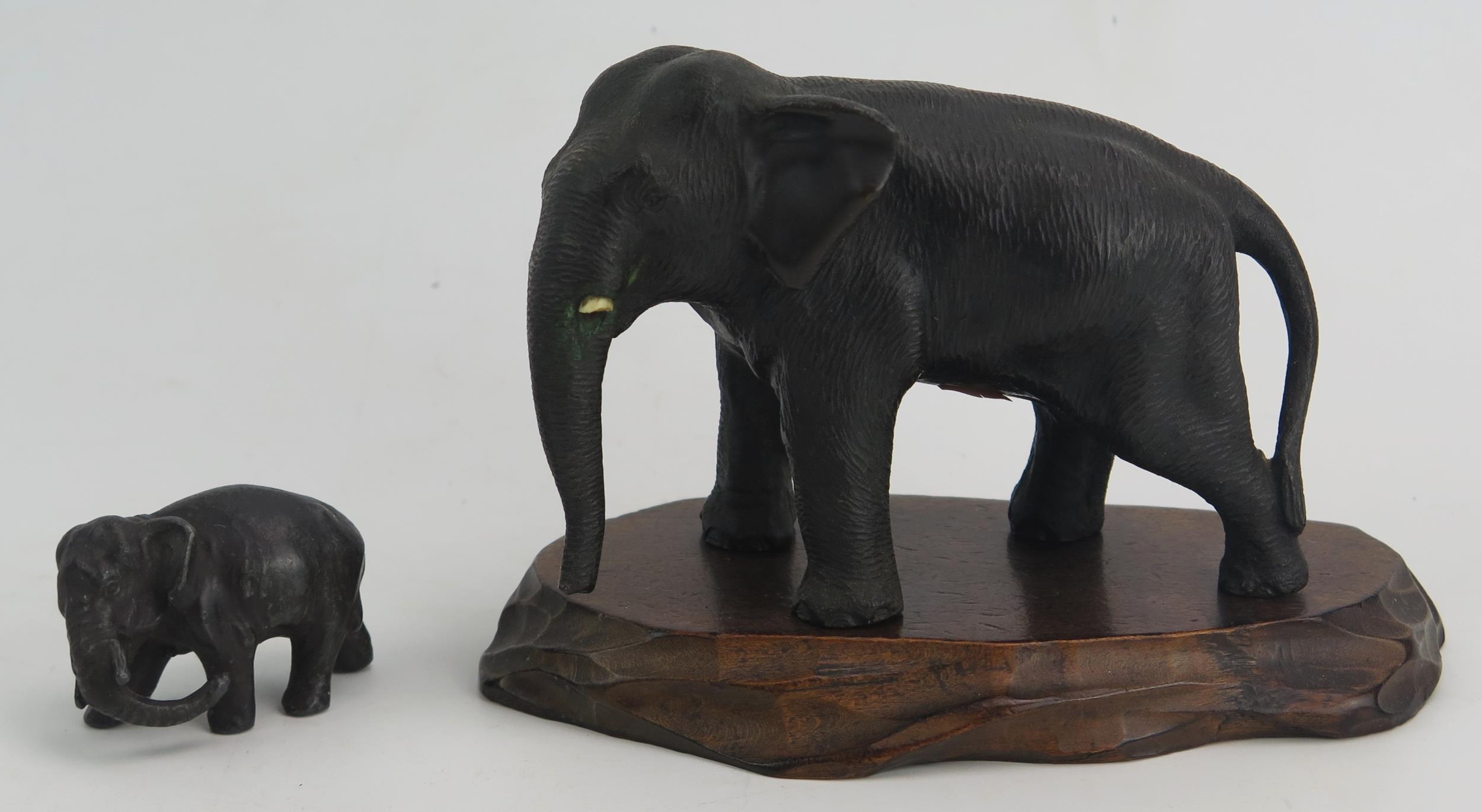 A Japanese Meiji Period Bronze Elephant (12cm long) and on a carved wooden stand and one signed