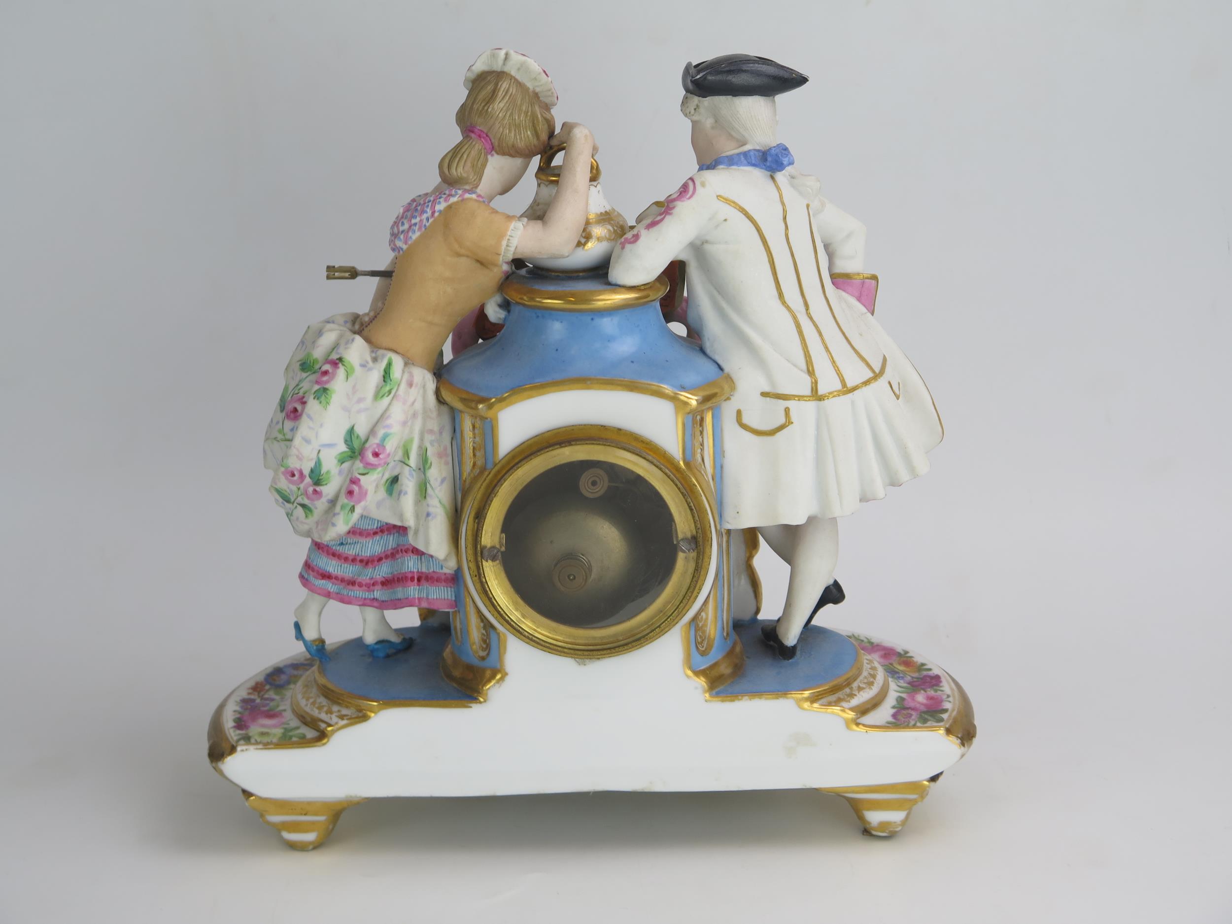 A 19th century French porcelain figural mantel clock, the urn-shaped case flanked by a gallant and - Image 2 of 2