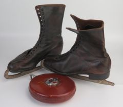 A pair of brown leather ice-skating boots with steel blades, together with a leather bound tape