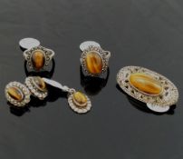 A selection of tiger's eye jewellery comprised of a string of cylindrical beads, an oval brooch