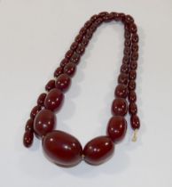 A string of cherry red Faturan amber graduated oval beads, 77cm long, 61.8g gross, the largest