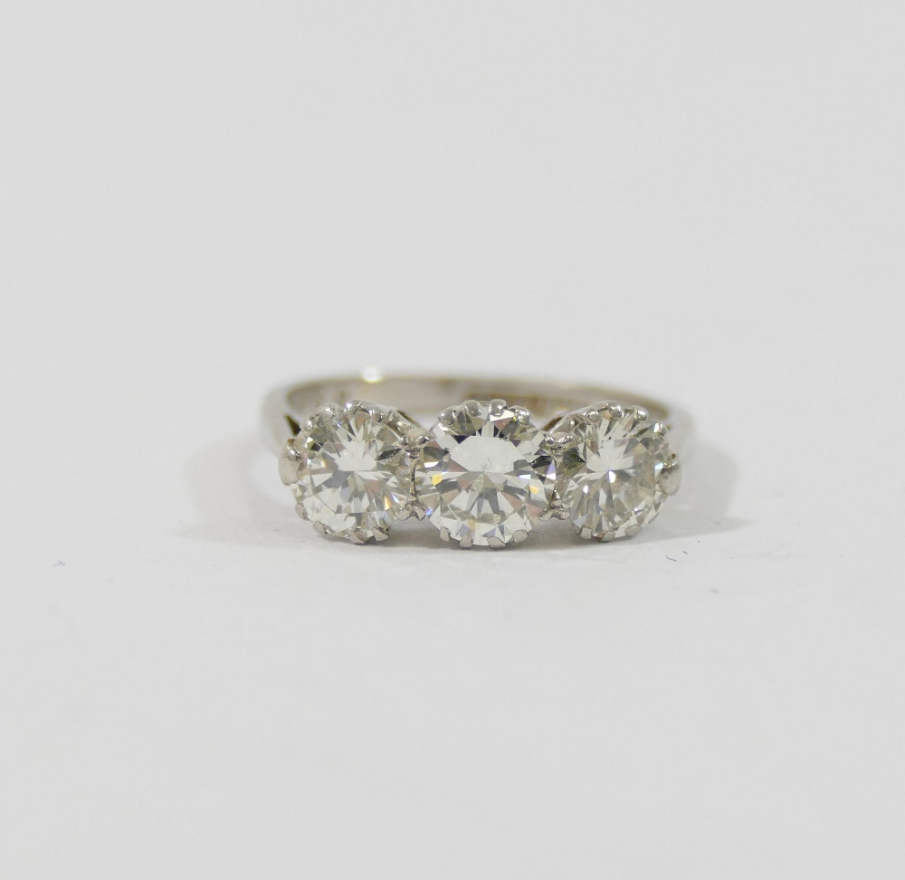 A mid-century platinum and diamond three-stone ring, the round brilliant cut stones combined