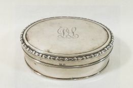 A silver oval hinged dressing table trinket box, with hinged lid engraved with scrolling initials,