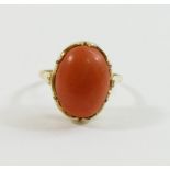 An oval coral cabochon in unmarked yellow metal ring mount, finger size K, 3.7g gross CONDITION